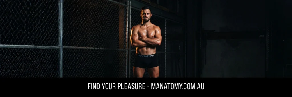 A man with arms crossed in front of a chain-link cage in a dark room, above a Find Your Pleasure banner.