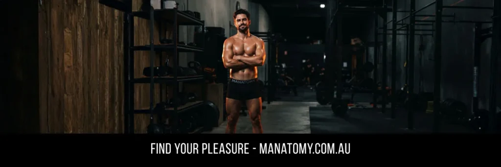 A man with arms crossed standing in a dark gym among weight racks, above a Find Your Pleasure banner.